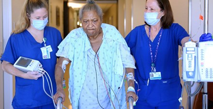 A hospital patient walks with the help of physical therapists