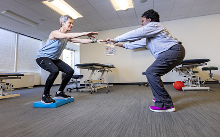 A physical therapist educating a patient on  how to perform a strength and balance exercise.