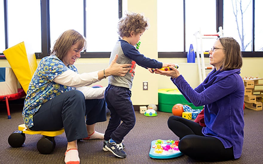 A physical therapist works with a child with cerebral palsy