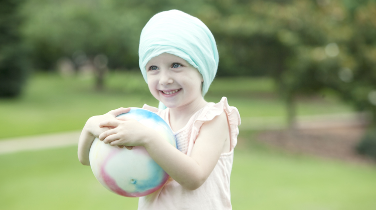A child with cancer holding ball.