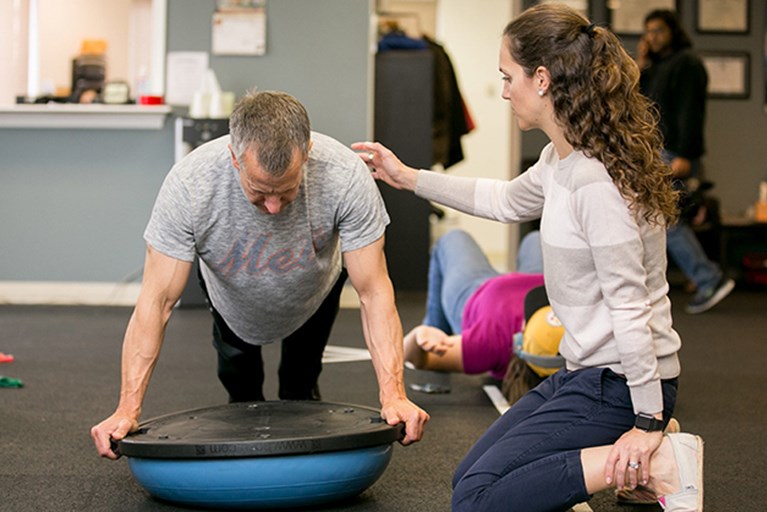 A physical therapist working with a patient on strengthening exercises