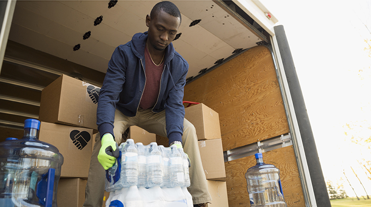 Man lifting water bottles out of moving van.