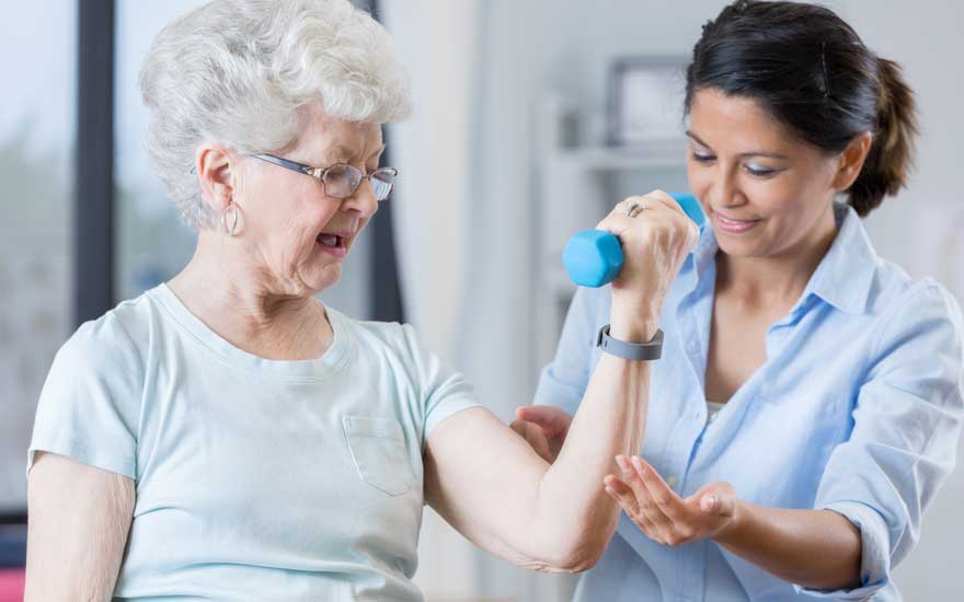 An older adult receives instruction for arm exercises from her physical therapist