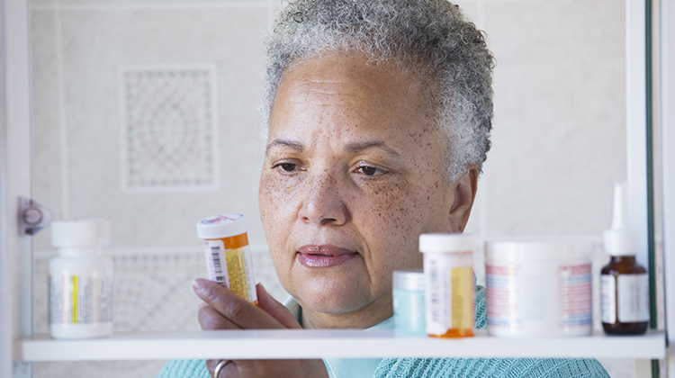 Woman taking medicine bottle out of medicine cabinet.