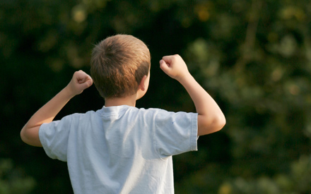 A young boy facing away from the camera doing fist pumps.