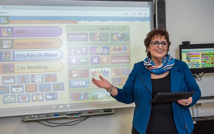 Patty standing in front of a smart board instructing a class