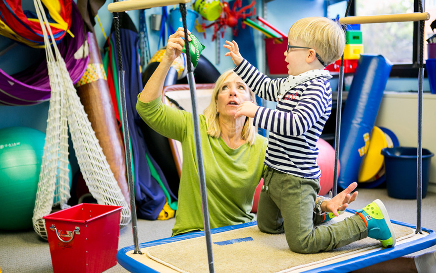 A physical therapist works with a child on balance and sensory processing.