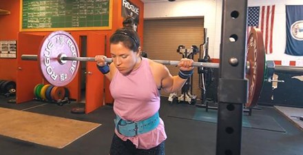 A female weightlifter prepares to do a squat.