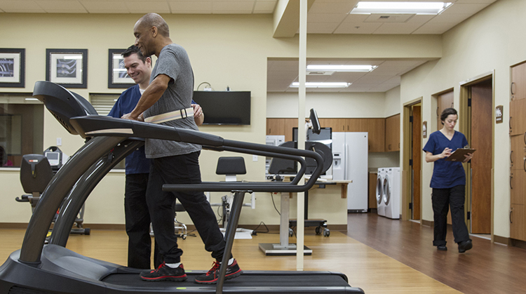 Older adult workng with a PT on treadmill.