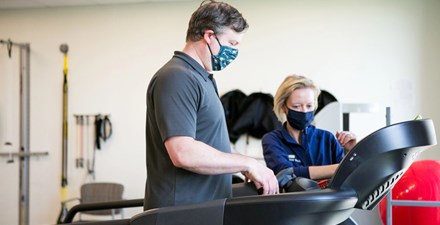 Physical therapist working with a patient on a treadmill.