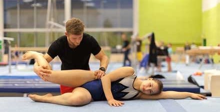 A sports physical therapist working on a gymnast's hip.