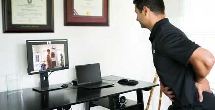 A physical therapist instructing a patient on an exercise over the computer.