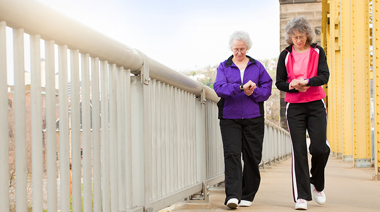 Two women with grey hair and glasses walking.