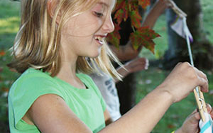 A young girl hooks clothes to a clothes line with a clothing pin.