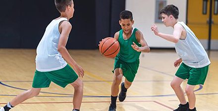 Young boys playing basketball in a gym.