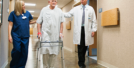 Male patient walking with a physical therapist and doctor in a hospital