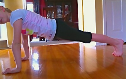 A child doing the plank exersize on the floor.